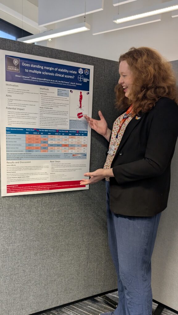 Olivia Stood in front of a poster presenting her research.